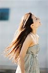 Young woman walking outdoors, long hair tousled by wind