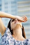 Woman holding back of hand over eye, head back