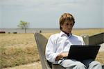 Man using laZSop computer outdoors, open field in background