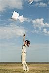 Woman outdoors tossing document into air