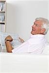 Senior homme lisant journal sur canapé