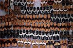 Many leather sandals on display at market.