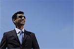 Indian businessman wearing sunglasses and smiling outside.