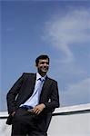 Indian businessman leaning on balcony.