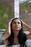 Indian woman looking up and holding her head