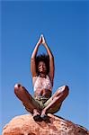 Woman sitting on rock looking up at sky