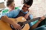 Man playing guitar and singing for woman on sofa