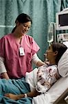 Infirmière de parler à la jeune fille dans son lit d'hôpital