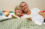 Couple d'âge mûr en lecture lit