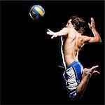 Studio shot of man jumping to hit soccer ball