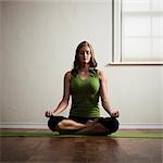 USA, Utah, Orem, young woman meditating in lotus position on exercise mat