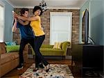 USA, Utah, Provo, young couple holding remote control in living room