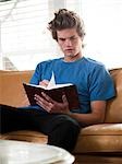 USA, Utah, Provo, young man reading book on sofa