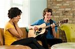 USA, Utah, Provo, young man playing guitar with young woman covering ears