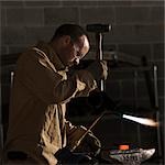 USA, Utah, Orem, man welding with hammer and blowtorch in workshop