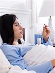 Orem, Utah, USA, jeune femme malade l dans le lit regardant le thermomètre