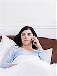 Orem, Utah, USA, junge kranke Frau im Bett reden auf Handy