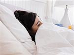 Orem, Utah, USA, junge Frau im Bett liegend mit Federn bedeckt.