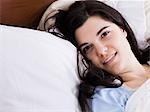 Orem, Utah, USA, young woman lying in bed smiling, portrait