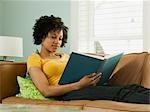 USA, Utah, Provo, junge Frau auf dem Sofa liegend und Buch zu lesen