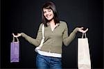 Studio portrait of young woman holding shopping bags