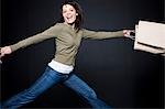 Studio portrait of young woman jumping with shopping bags