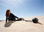 USA, Utah, Little Sahara, young businesswoman pulling ball in chain on desert