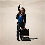 USA, Utah, Little Sahara, young businesswoman standing on desert shielding sun with arm