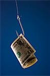 One US dollar bill on hook, against blue background