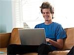 USA, Utah, Provo, young man sitting on sofa and using laptop