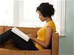 USA, Utah, Provo, jeune femme lisant livre sur canapé, côté vue