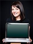 Young woman showing laptop, studio shot