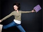 Jeune femme avec des sacs à provisions sautant, studio shot