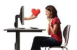 Conceptual picture of young woman receiving red heart out of her computer