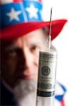 Man in Uncle Sam's costume holding syringe with us dollar banknote inside, studio shot