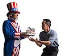 Man in Uncle Sam's costume giving model of house to other man, studio shot