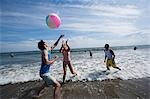 Three adults playing with a beach ball