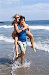 Man carrying woman through shallow water at the beach