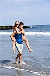 Homme portant la femme à la plage