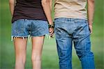 Jeune couple marchant sur un pelouse bras