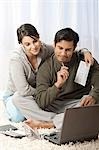 Man and woman on carpet with laptop