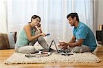 Man and woman on carpet with laptops