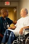 Homme d'âge mûr en fauteuil roulant avec un médecin et une infirmière