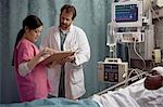 Doctor looking at medical chart of boy in hospital bed