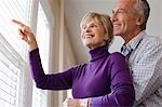 Mature couple looking through blinds