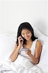 Female in bed with cell phone and laptop