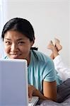 Female on bed with laptop and cell phone