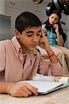 Boy doing homework with girl talking on phone