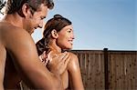 Man applying suntan lotion to woman's back
