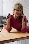 Mature woman talking on telephone in kitchen